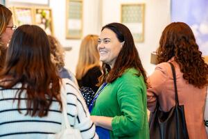 Attendees mingling in the exhibition hall, with one smiling.