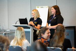 Two presenters at a lectern presenting to audience