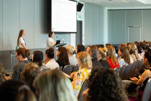 Two presenters presenting to rows of attendees