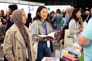 Two attendees speaking to an exhibitor
