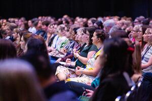 Rows of attendees watching a presenter 