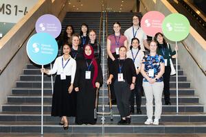 2024 Student volunteers standing on stairs holding four large lollipops sign