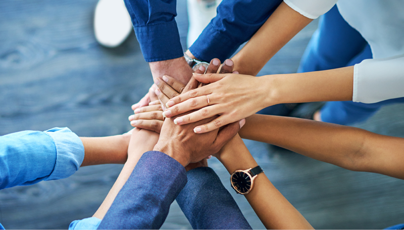 This is a photo of people putting their hands together in a circle.