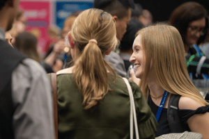 Attendees mingling, with one facing away from the camera and another in side profile. 